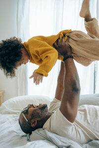 lucky man playing with his child on a bed